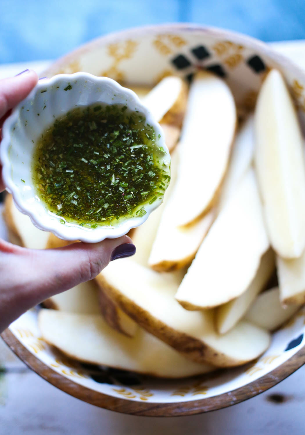 adding seasonings and olive oil to potato wedges