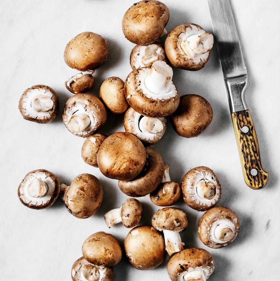 baby bella mushrooms on marble cutting board